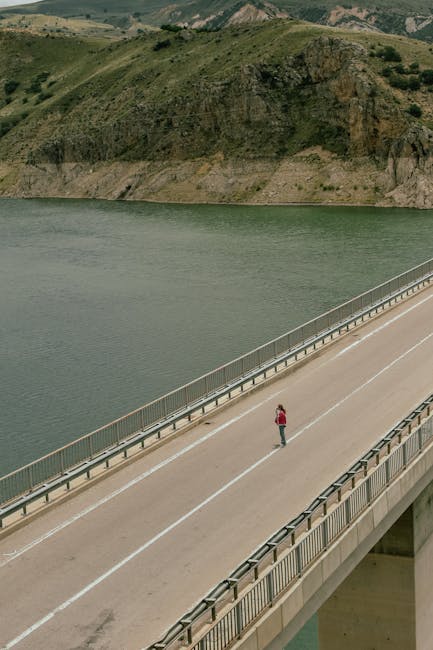 A person walking on a long bridge over a lake