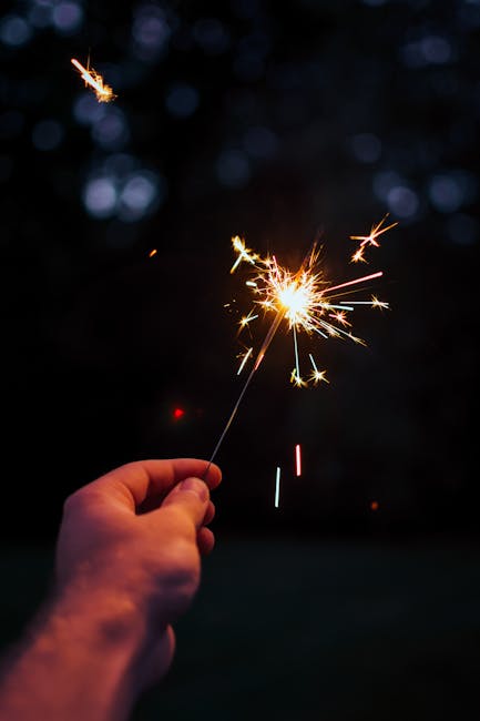 Hand holding a lit sparkler at night